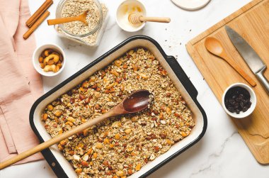Beyaz mermer bir arka planda ev yapımı granola, kurutulmuş kızılcık ve bal kabı, üst manzara..