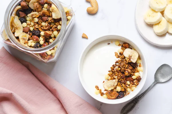 Sağlıklı kahvaltı - yoğurtlu granola, fındık ve muz dilimleri, üst manzara.