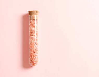 Himalaya pembe tuzu pembe arka planda tıpası olan cam bir kapta. Yatay biçim.