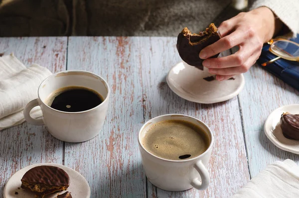 女の子飲むコーヒーと食べるチョコレートAlfajores上の木のテーブル — ストック写真