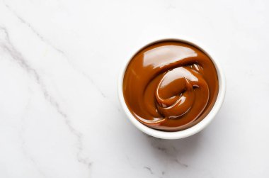 Fotokopi alanı olan beyaz mermer arka planda bir kase dolusu dulce de leche. 