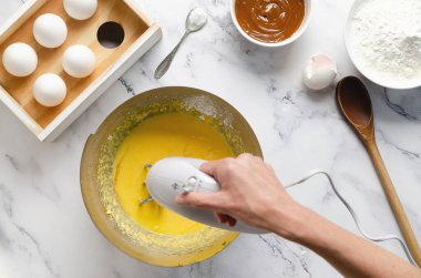 Kurabiye ve mısır nişastası yapmak için malzemeleri karıştırıyorum. Yumurta, tereyağı, mısır nişastası, kabartma tozu ve beyaz mermer arka planda dulce de leche..