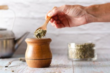 Dişi bir el, Yerba 'nın eşini, Yerba' nın eşini bir bardak ve bir çaydanlık içine koyuyor..