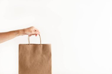 Beyaz arka planda alışveriş poşeti tutan bir kadının eli..