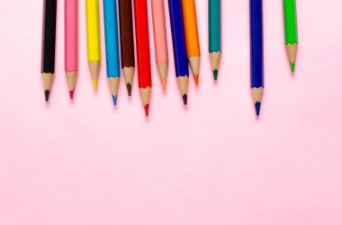 Pembe arka planda keskinleştirilmiş renkli kalem koleksiyonu.