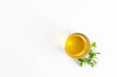 Şeffaf bir fincan nane çayı ve beyaz arka planda taze nane yaprakları. Kopyalama alanı olan üst görünüm.