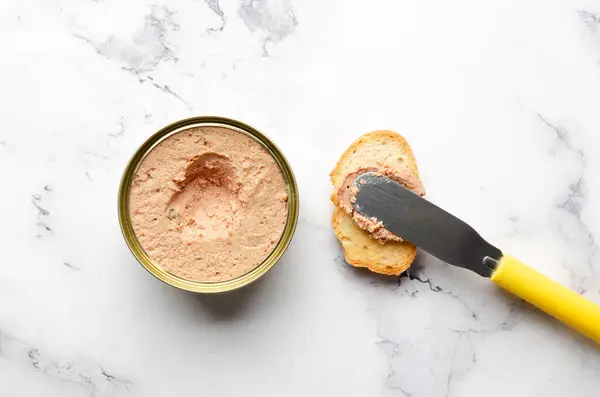 Bir parça ekmeğin üzerine yayılan bir bıçak ve kopya uzayı olan bir mermer yüzeye konserve konservesi. Gıda koruma kavramı.