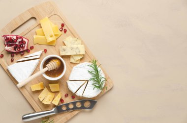 Çeşitli peynir, bal, nar tohumu ve ahşap tahtada biberiye yaprakları ve fotokopi alanı olan bej arka plan çeşitleri. Üst görünüm ve yatay biçim.