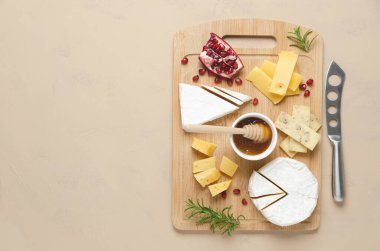 Çeşitli peynir, bal, nar tohumu ve ahşap tahtada biberiye yaprakları ve fotokopi alanı olan bej arka plan çeşitleri. Üst görünüm ve yatay biçim.