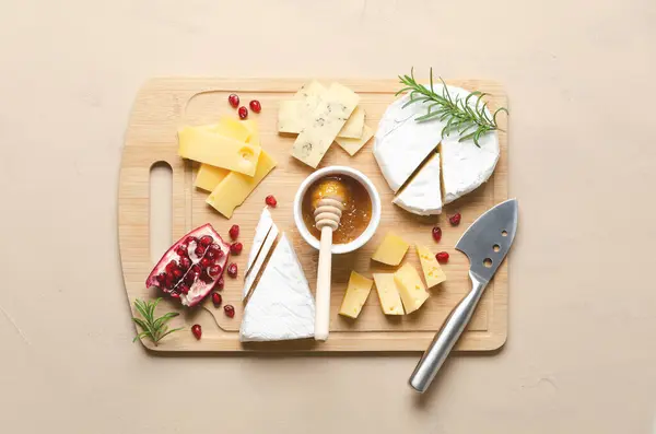 Çeşitli peynir, bal, nar tohumu ve ahşap tahta ve bej arka planda biberiye yaprakları. Üst görünüm ve yatay biçim.