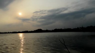 Bulutlu gökyüzünün güzelliği ve nehirdeki turuncu güneş.