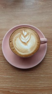 Köpüklü süt köpüklü dumanı tüten bir bardak kapuçino, altında bol espresso, sıcak kahve anlarını ısıtmak için sıcak servis edilir..