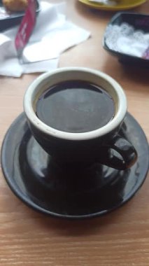 Dumanı tüten siyah bir Americano kahvesi, zengin ve koyu, basit bir fincanda servis ediliyor, ferahlatıcı ve aromatik bir kahve deneyimi için mükemmel..