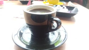 Dumanı tüten siyah bir Americano kahvesi, zengin ve koyu, basit bir fincanda servis ediliyor, ferahlatıcı ve aromatik bir kahve deneyimi için mükemmel..