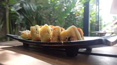 Taze malzemelerle lezzetli bir suşi rulosu, aroma ve dokuların mükemmel dengesi, yosunla sarılmış ve sosla servis edilmiş.