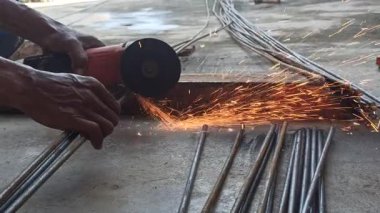 Bir işçi, keskin bir bıçak kullanarak kalın çelik parmaklıkları keser. Bıçak keskin ve hassas bir şekilde kesilirken kıvılcımlar oluşturur.