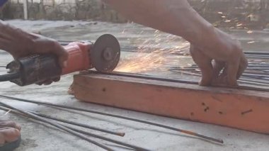 Bir işçi, keskin bir bıçak kullanarak kalın çelik parmaklıkları keser. Bıçak keskin ve hassas bir şekilde kesilirken kıvılcımlar oluşturur.