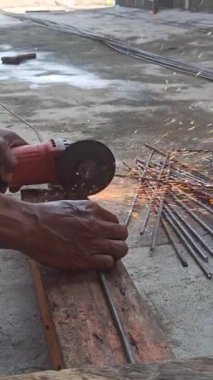 Bir işçi, keskin bir bıçak kullanarak kalın çelik parmaklıkları keser. Bıçak keskin ve hassas bir şekilde kesilirken kıvılcımlar oluşturur.