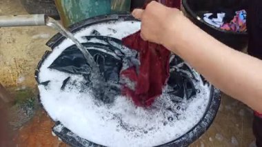 Eller sabunlu su dolu bir havuzda giysileri ovalıyor, geleneksel el yıkama yöntemlerini, günlük ev işlerini ve basit ev yaşamını yakalıyor..