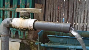 Basit bir musluk günlük su ihtiyacını karşılıyor, açık havada kuruluyor, temel faydaları ve temiz suya pratik erişimi gösteriyor.