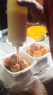 Takoyaki, lezzetli, ışıltılı ve ağız sulandırıcı bir sunum hazırlayarak, pürüzsüz çizgilerde tuzlu sosla kaplıdır..