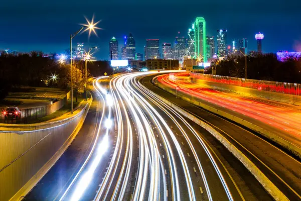 Dallas skyline by night The rush hour traffic leaves light trails on I-30 Tom Landry freeway.
