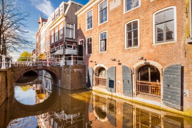 Historic buildings border a canal, along Wijnhaven street, near Waagbrug bridge, in the old center of Delft, The Netherlands. clipart