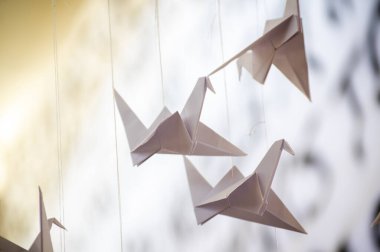 Japanese folded Origami cranes hanging on with strings. Hundreds handmade paper birds isolated with copy space. 1000 thousand crane tsuru sculpture topic. Symbol of peace, faith, health, wishes, hope