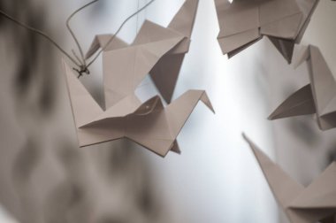 Japanese folded Origami cranes hanging on with strings. Hundreds handmade paper birds isolated with copy space. 1000 thousand crane tsuru sculpture topic. Symbol of peace, faith, health, wishes, hope