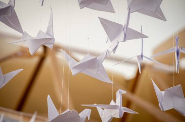 Japanese folded Origami cranes hanging on with strings. Hundreds handmade paper birds isolated with copy space. 1000 thousand crane tsuru sculpture topic. Symbol of peace, faith, health, wishes, hope