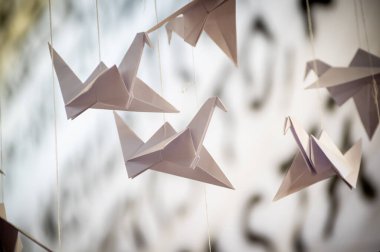 Japanese folded Origami cranes hanging on with strings. Hundreds handmade paper birds isolated with copy space. 1000 thousand crane tsuru sculpture topic. Symbol of peace, faith, health, wishes, hope