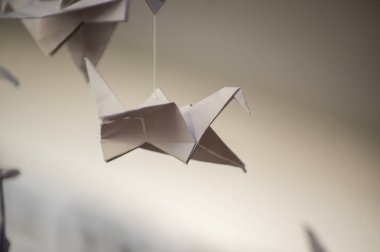 Japanese folded Origami cranes hanging on with strings. Hundreds handmade paper birds isolated with copy space. 1000 thousand crane tsuru sculpture topic. Symbol of peace, faith, health, wishes, hope