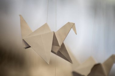 Japanese folded Origami cranes hanging on with strings. Hundreds handmade paper birds isolated with copy space. 1000 thousand crane tsuru sculpture topic. Symbol of peace, faith, health, wishes, hope