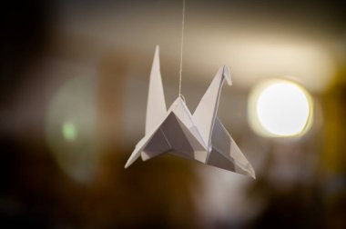Japanese folded Origami cranes hanging on with strings. Hundreds handmade paper birds isolated with copy space. 1000 thousand crane tsuru sculpture topic. Symbol of peace, faith, health, wishes, hope