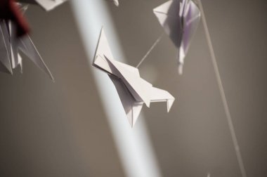 Japanese folded Origami cranes hanging on with strings. Hundreds handmade paper birds isolated with copy space. 1000 thousand crane tsuru sculpture topic. Symbol of peace, faith, health, wishes, hope