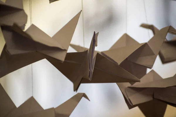 Japanese folded Origami cranes hanging on with strings. Hundreds handmade paper birds isolated with copy space. 1000 thousand crane tsuru sculpture topic. Symbol of peace, faith, health, wishes, hope
