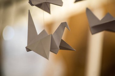 Japanese folded Origami cranes hanging on with strings. Hundreds handmade paper birds isolated with copy space. 1000 thousand crane tsuru sculpture topic. Symbol of peace, faith, health, wishes, hope