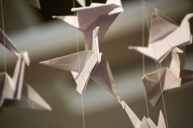 Japanese folded Origami cranes hanging on with strings. Hundreds handmade paper birds isolated with copy space. 1000 thousand crane tsuru sculpture topic. Symbol of peace, faith, health, wishes, hope