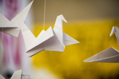 Japanese folded Origami cranes hanging on with strings. Hundreds handmade paper birds isolated with copy space. 1000 thousand crane tsuru sculpture topic. Symbol of peace, faith, health, wishes, hope