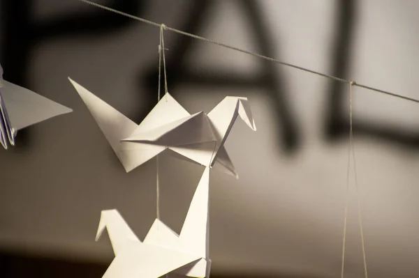 Japanese folded Origami cranes hanging on with strings. Hundreds handmade paper birds isolated with copy space. 1000 thousand crane tsuru sculpture topic. Symbol of peace, faith, health, wishes, hope