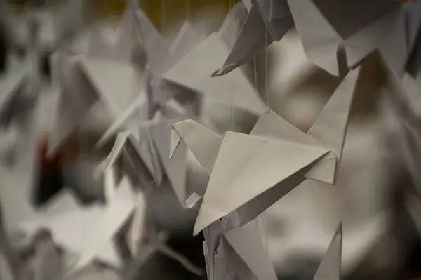 Japanese folded Origami cranes hanging on with strings. Hundreds handmade paper birds isolated with copy space. 1000 thousand crane tsuru sculpture topic. Symbol of peace, faith, health, wishes, hope