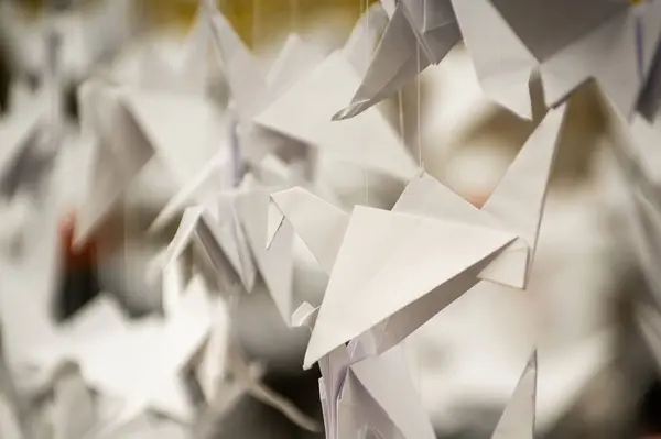Japanese folded Origami cranes hanging on with strings. Hundreds handmade paper birds isolated with copy space. 1000 thousand crane tsuru sculpture topic. Symbol of peace, faith, health, wishes, hope