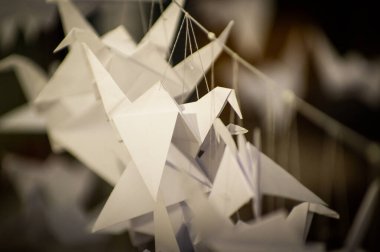 Japanese folded Origami cranes hanging on with strings. Hundreds handmade paper birds isolated with copy space. 1000 thousand crane tsuru sculpture topic. Symbol of peace, faith, health, wishes, hope