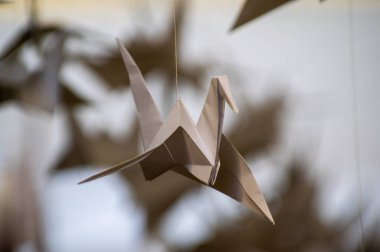 Japanese folded Origami cranes hanging on with strings. Hundreds handmade paper birds isolated with copy space. 1000 thousand crane tsuru sculpture topic. Symbol of peace, faith, health, wishes, hope