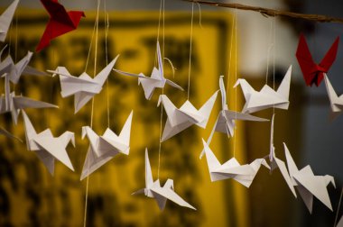 Japanese folded Origami cranes hanging on with strings. Hundreds handmade paper birds isolated with copy space. 1000 thousand crane tsuru sculpture topic. Symbol of peace, faith, health, wishes, hope