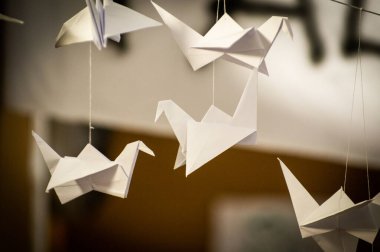 Japanese folded Origami cranes hanging on with strings. Hundreds handmade paper birds isolated with copy space. 1000 thousand crane tsuru sculpture topic. Symbol of peace, faith, health, wishes, hope