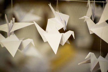 Japanese folded Origami cranes hanging on with strings. Hundreds handmade paper birds isolated with copy space. 1000 thousand crane tsuru sculpture topic. Symbol of peace, faith, health, wishes, hope
