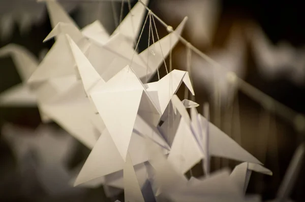 Japanese folded Origami cranes hanging on with strings. Hundreds handmade paper birds isolated with copy space. 1000 thousand crane tsuru sculpture topic. Symbol of peace, faith, health, wishes, hope