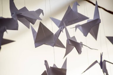 Japanese folded Origami cranes hanging on with strings. Hundreds handmade paper birds isolated with copy space. 1000 thousand crane tsuru sculpture topic. Symbol of peace, faith, health, wishes, hope