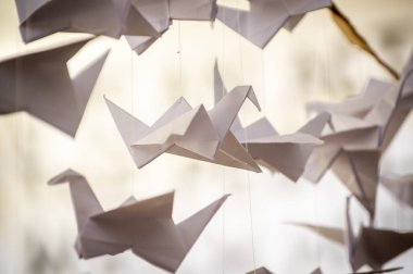 Japanese folded Origami cranes hanging on with strings. Hundreds handmade paper birds isolated with copy space. 1000 thousand crane tsuru sculpture topic. Symbol of peace, faith, health, wishes, hope